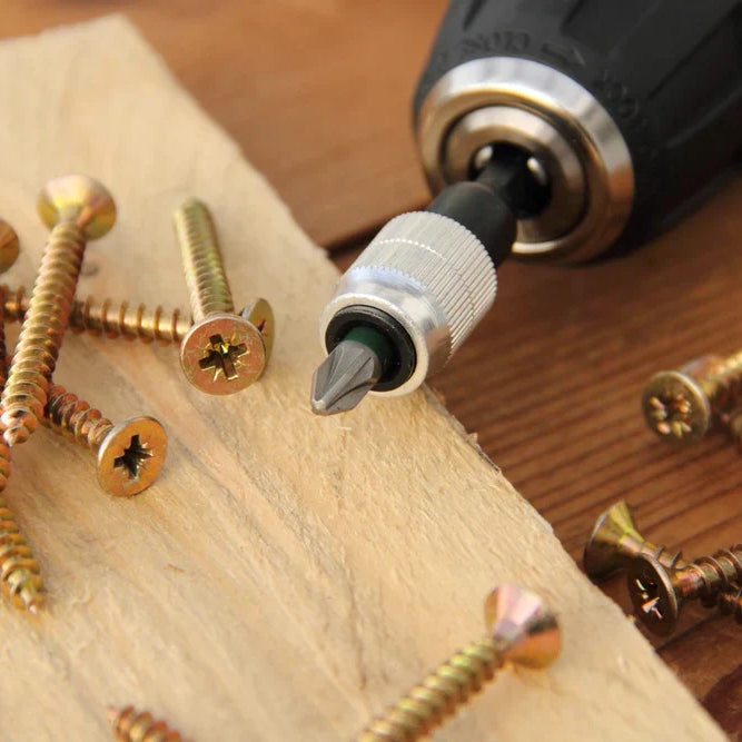 wood screws on a plank of wood near a hand drill